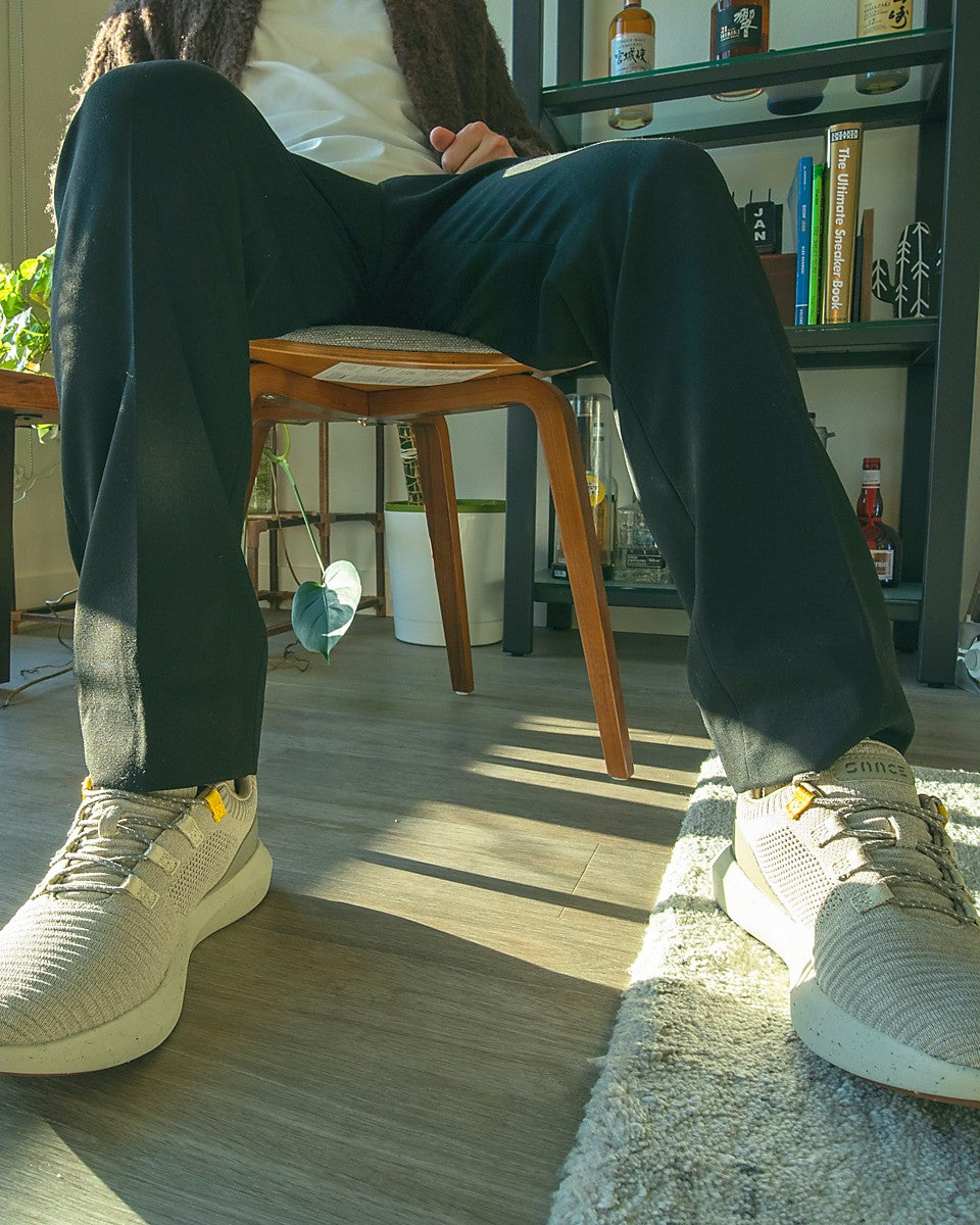 Man sitting in chair inside room in front of plants and wearing SNNCE sneakers