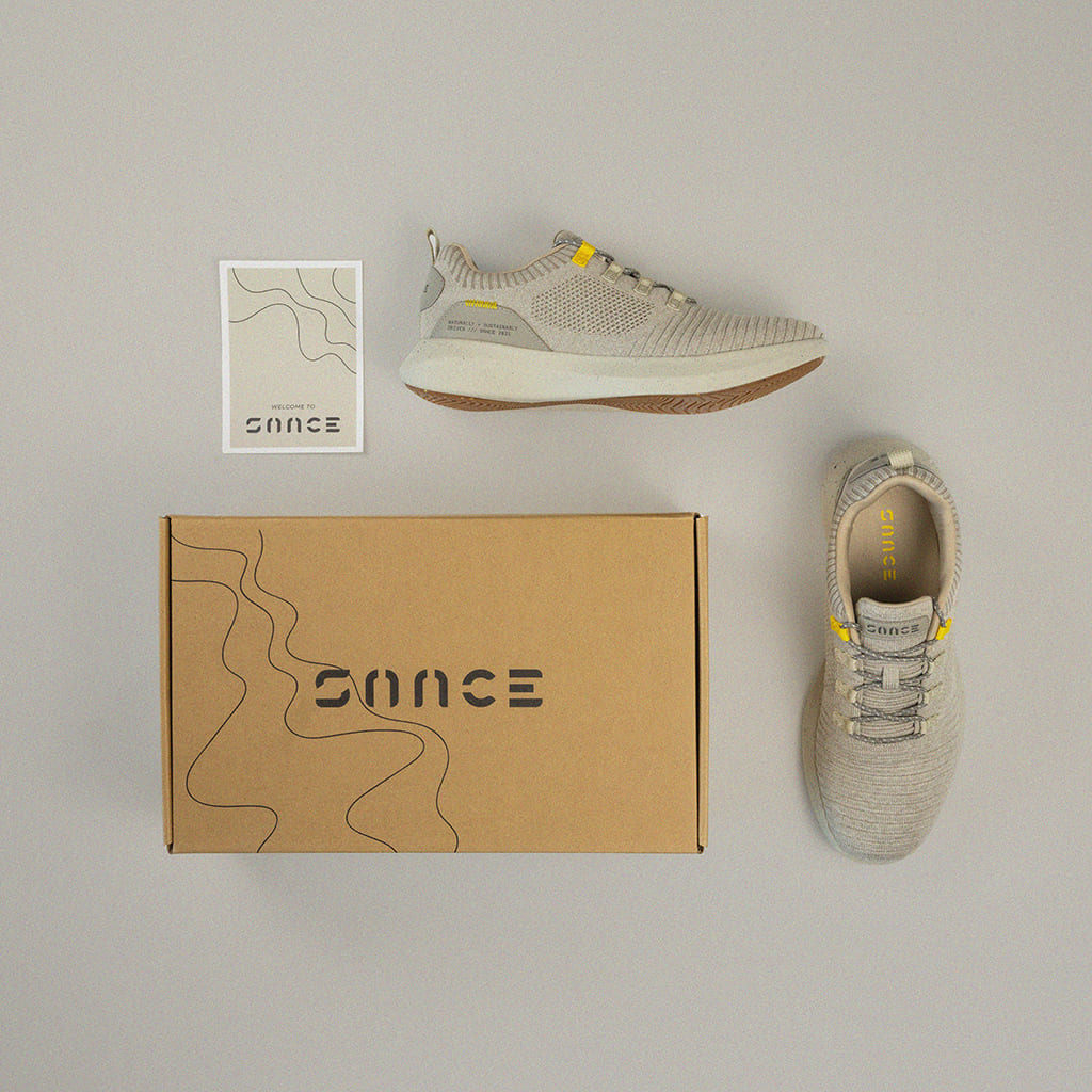 Flatlay image of both sneakers and the packaging organized neatly on neutral grey background